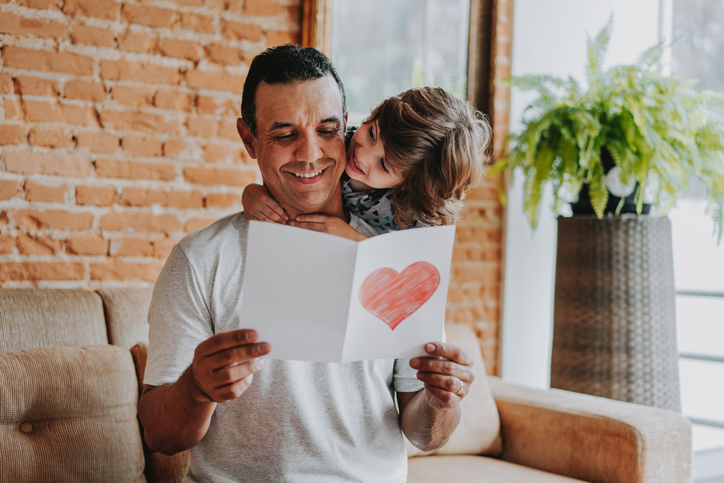 Son handing postcard to father on father's day